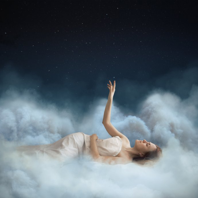 A woman in a white dress lying on clouds with her hand raised towards a starry sky.