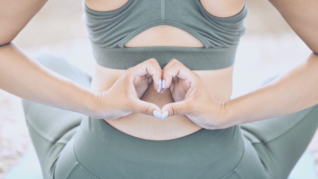 Individual forming a heart shape with their hands against their back while seated in a yoga pose.