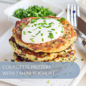 Courgette fritters topped with tahini yoghurt and chopped chives, served on a plate.
