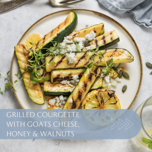 Plate of grilled courgette topped with goat's cheese, honey, walnuts, and garnished with fresh herbs.