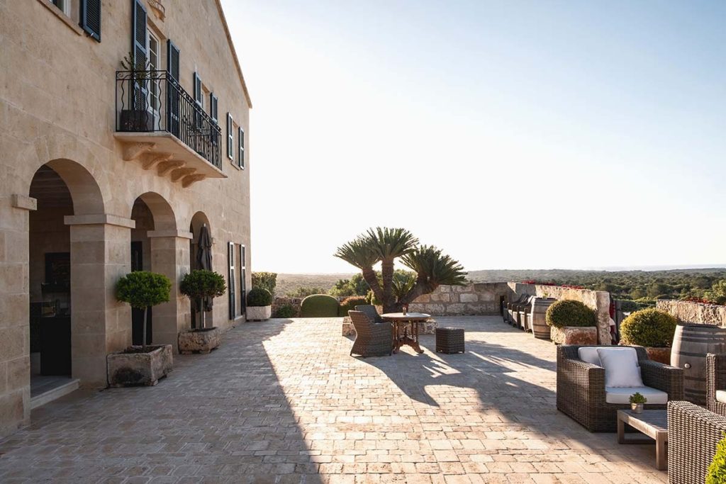Exterior view of a villa featuring a spacious outdoor seating area with wicker furniture and potted plants.