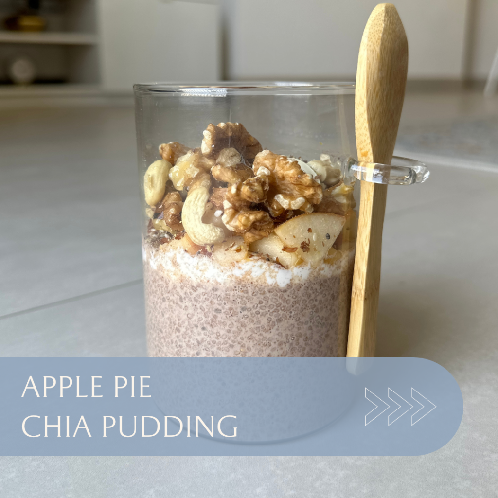 Chia pudding layered with apple pieces, nuts, and caramel popcorn served in a glass with a wooden spoon.