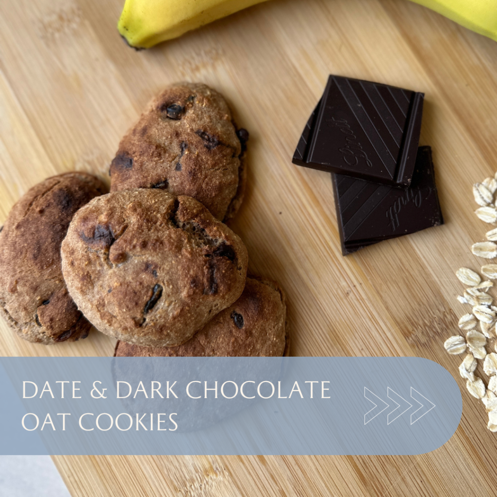 Date and dark chocolate oat cookies arranged on a wooden surface with a banana and chocolate pieces.