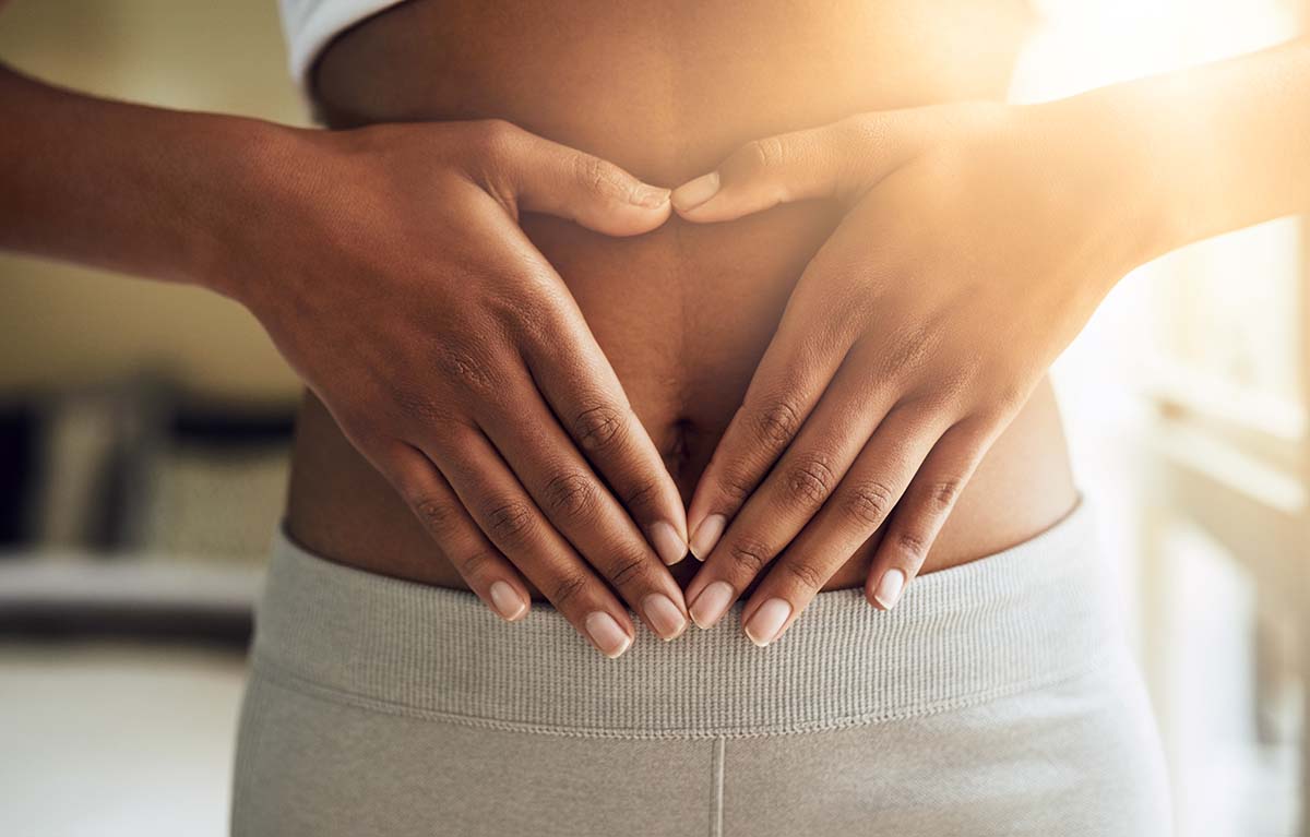 Individual with hands placed on their stomach, showcasing a neutral pose with a focus on the midsection.