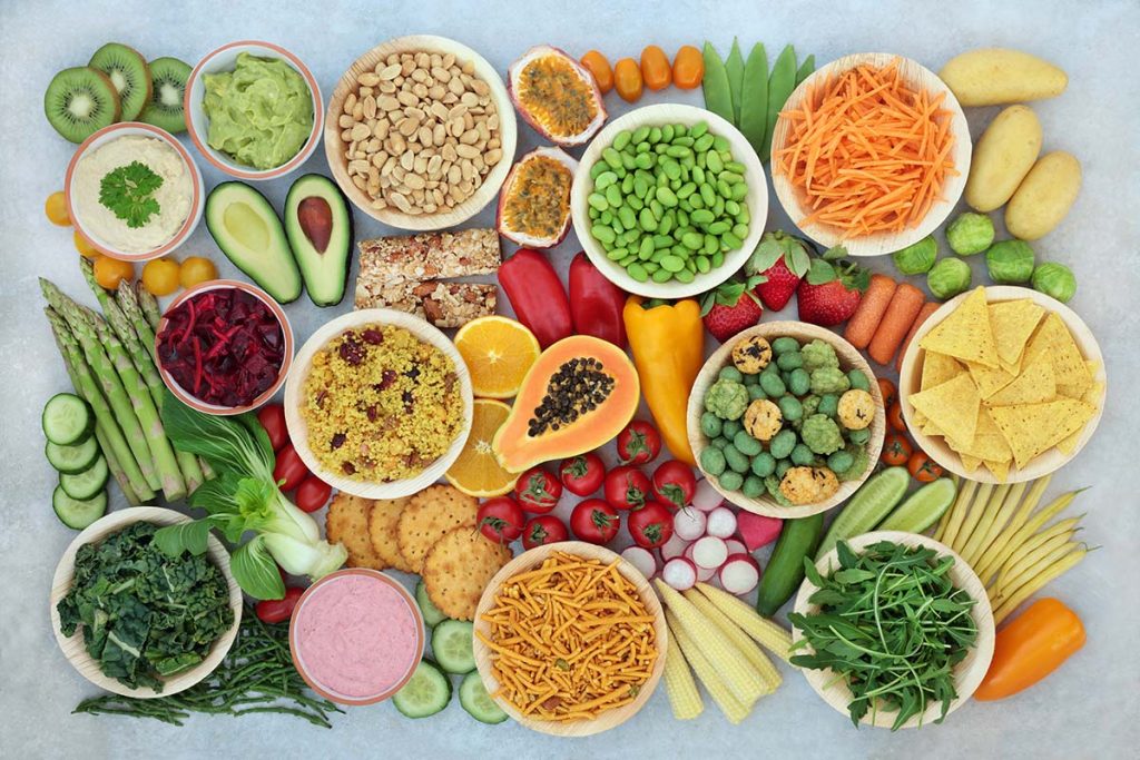 Variety of fresh fruits and vegetables arranged in bowls, including carrots, strawberries, and avocados.