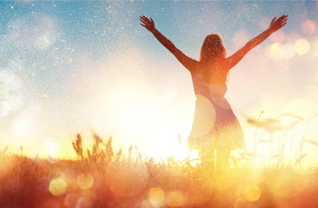 Silhouette of a woman with arms raised against a bright, glowing background, representing a sense of freedom and positivity.