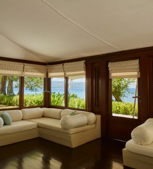 Lounge area featuring a light-coloured sofa with cushions and large windows overlooking a scenic view.