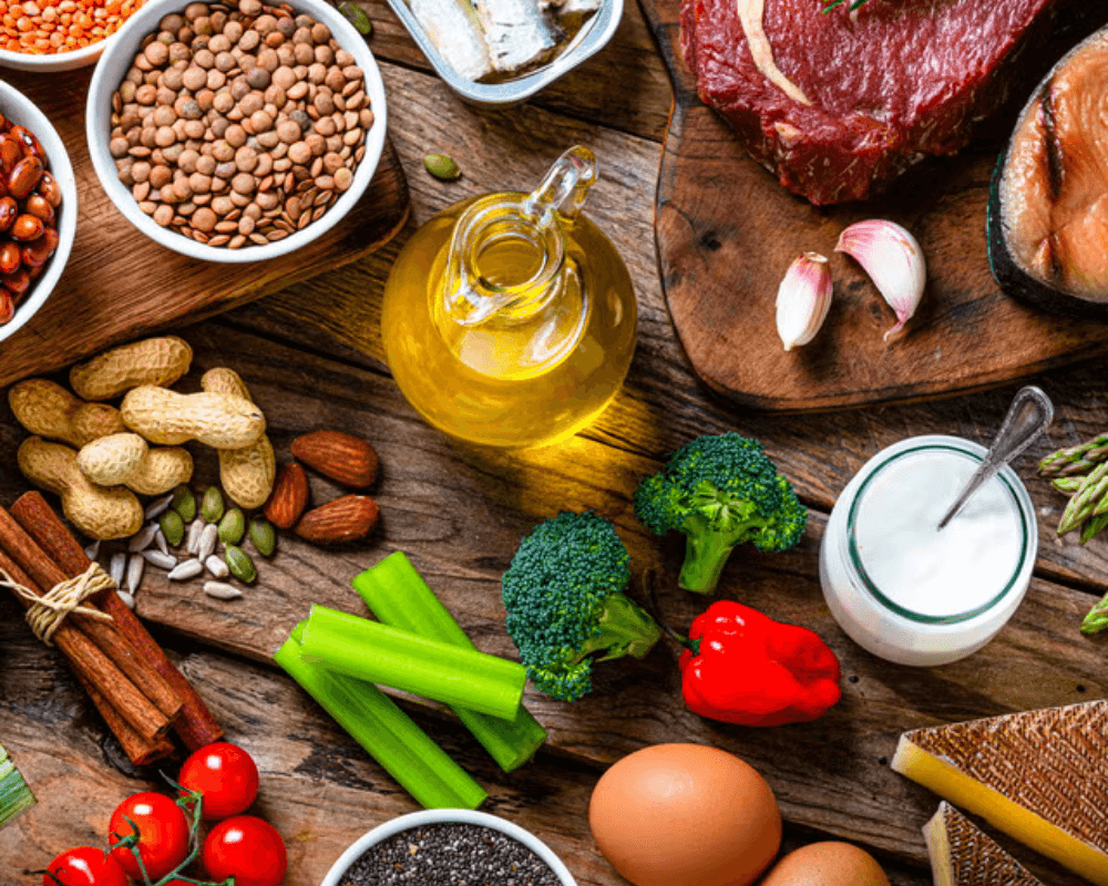 Variety of food ingredients including vegetables, oil, eggs, and spices arranged on a wooden surface.