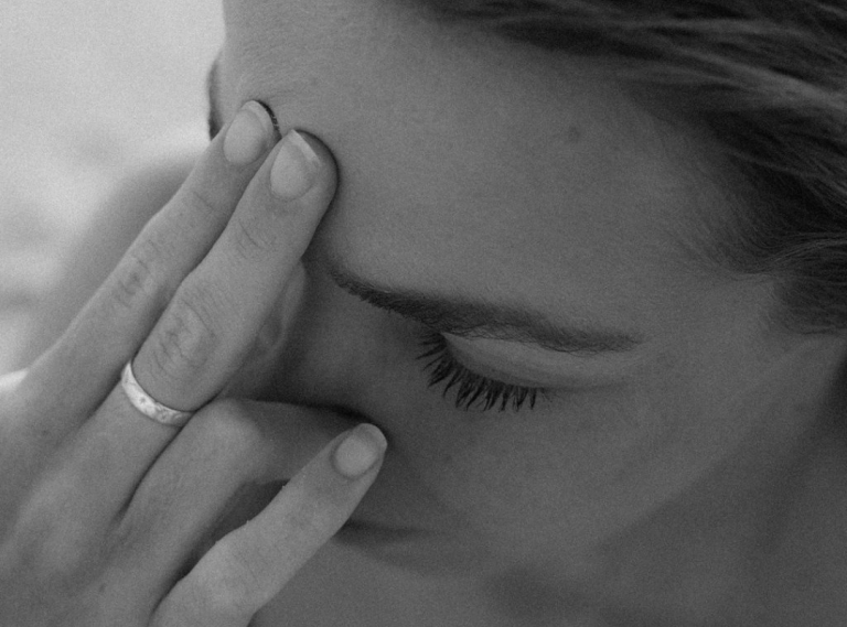 Monochrome close-up of a person with eyes closed, fingertips touching the temple, wearing a ring; associated with Andrew Huberman’s focus techniques and Silver Linings Wellbeing